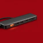 Hub USB-C com porta aquecida sobre fundo vermelho representando risco elétrico e perigo de dano ao notebook